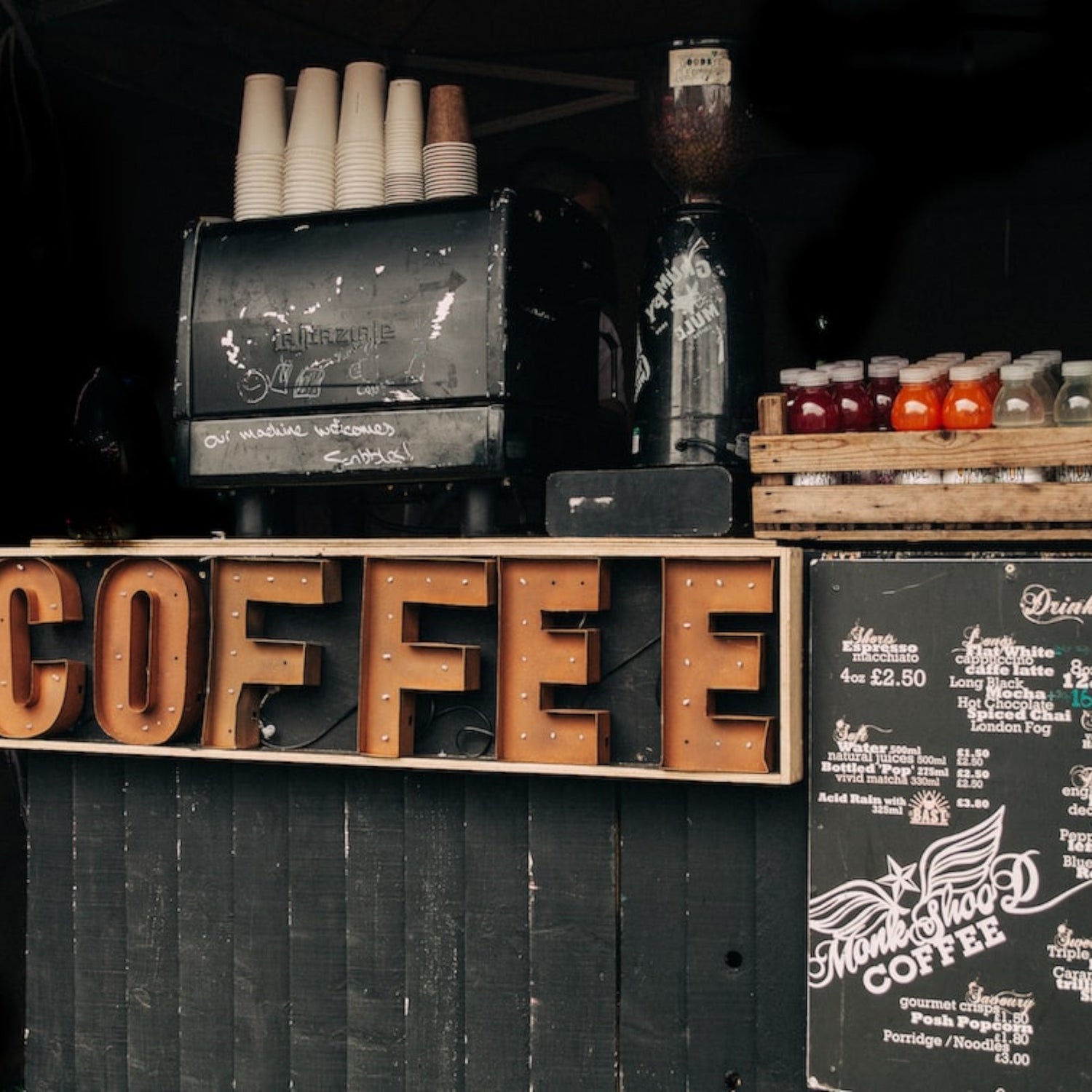 An old coffee bar with a chalkboard menu, drinks and cups.